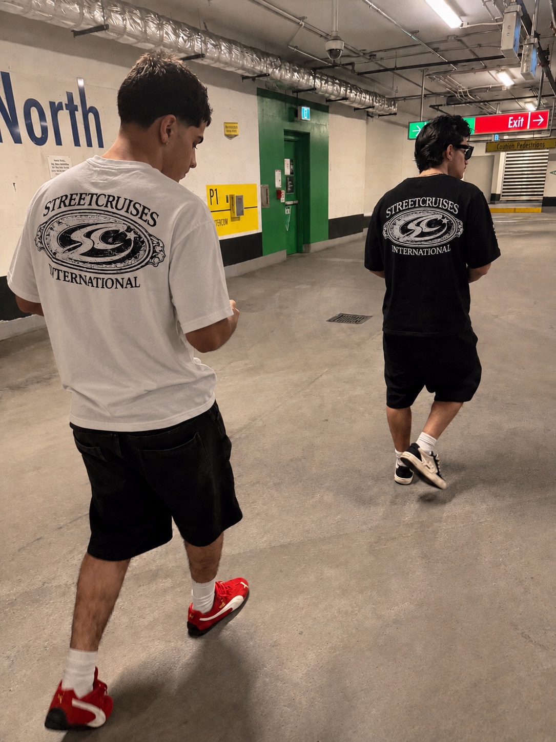 Two people wearing the white and black Streetcruises International tees