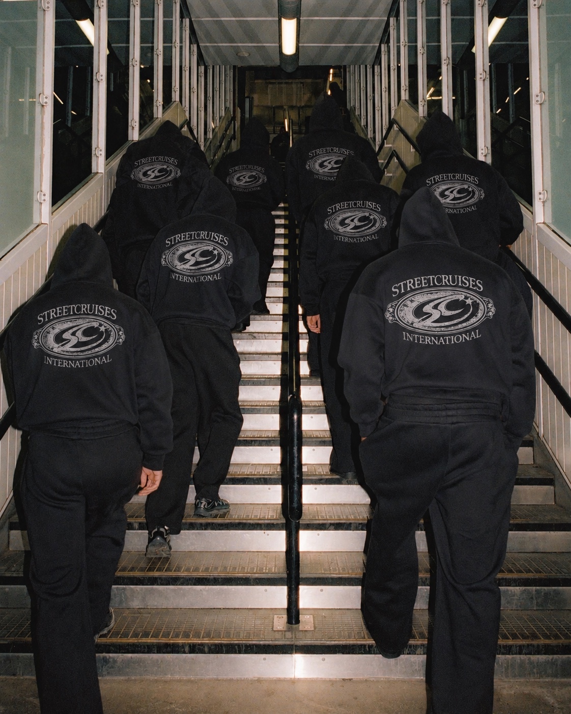 Streetcruises hoodie crew walking up a stairway with back graphics visible